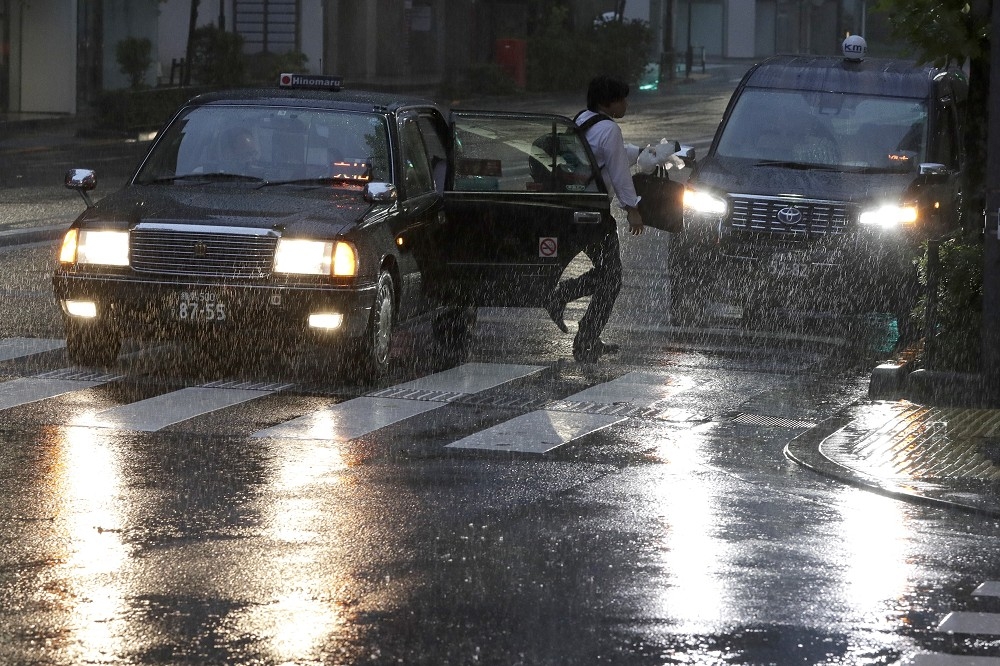 2019年東京暴雨中的計程車。日本典型的計程車車牌為綠色，與一般私家車的白色車牌有別。（資料照片／美聯社）