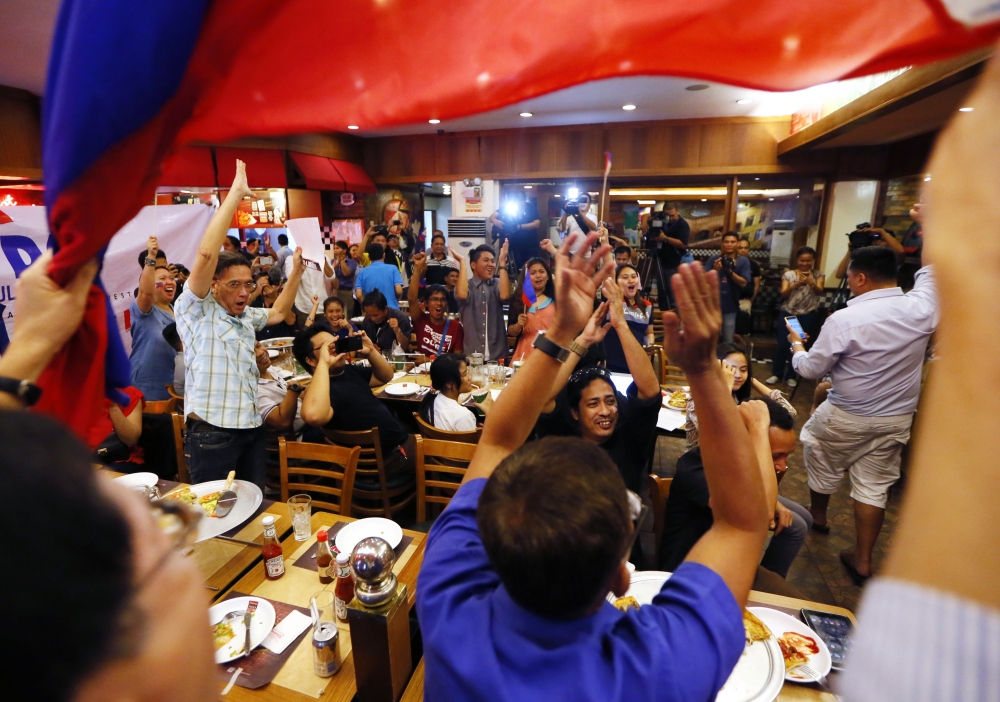 菲律賓民眾得知南海仲裁案結果後，舉起手大聲歡呼。  （美聯社）