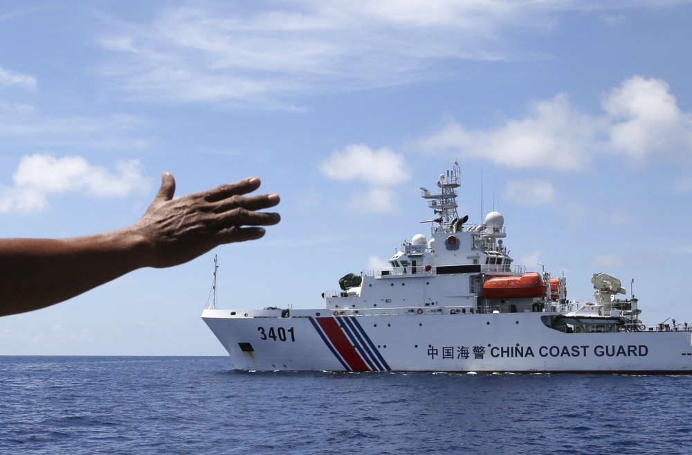 2014年3月29日，菲律賓海軍人員向一艘中國海警船揮手，要求對方讓他們進入仁愛礁。  （美聯社）