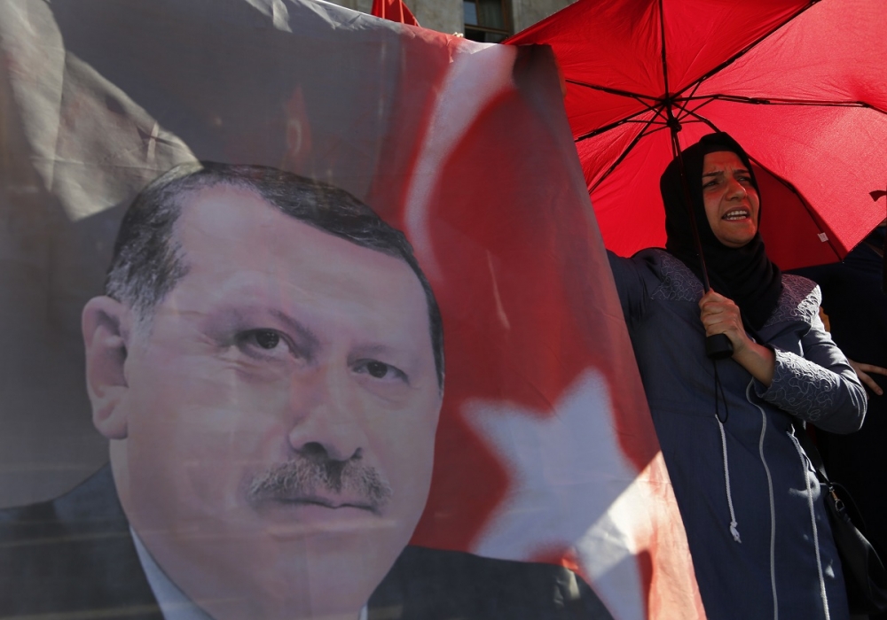 一名反軍方政變的女性站在土耳其總統艾爾多安的圖像旁（美聯社）