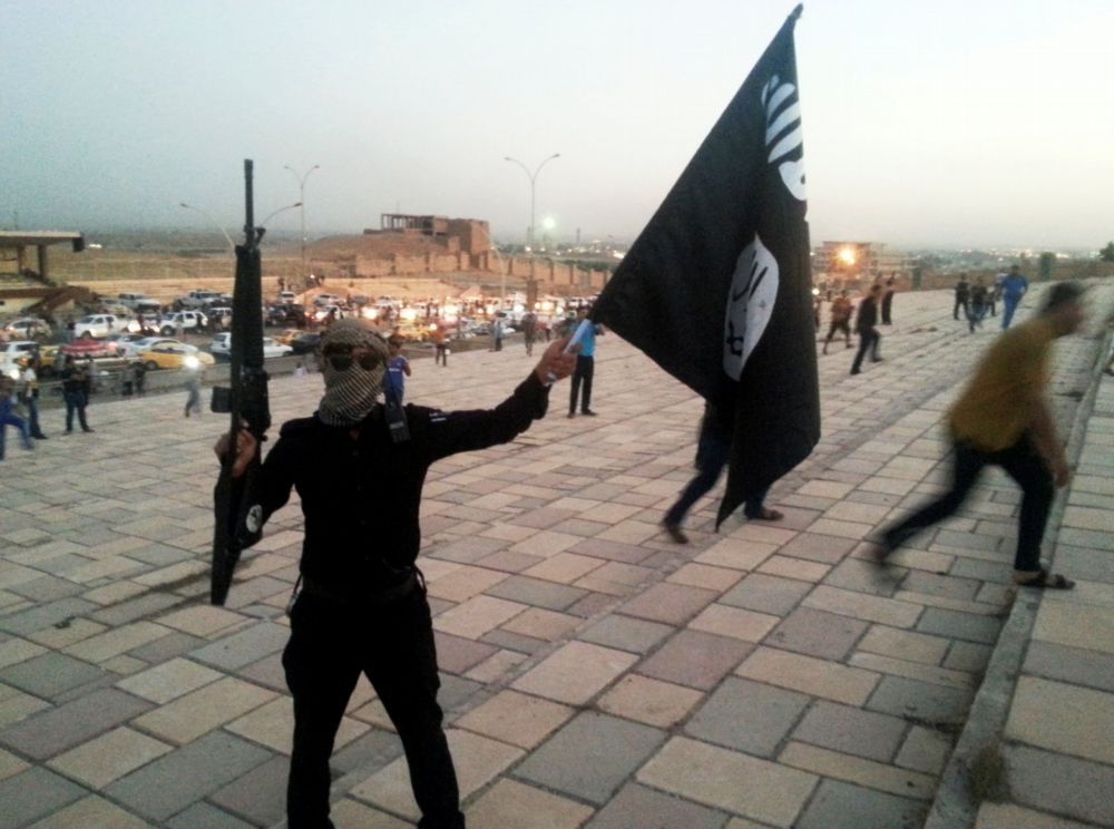 1名伊斯蘭國聖戰士在伊拉克大城摩蘇爾（Mosul）揮舞伊斯蘭國黑旗。（湯森路透）