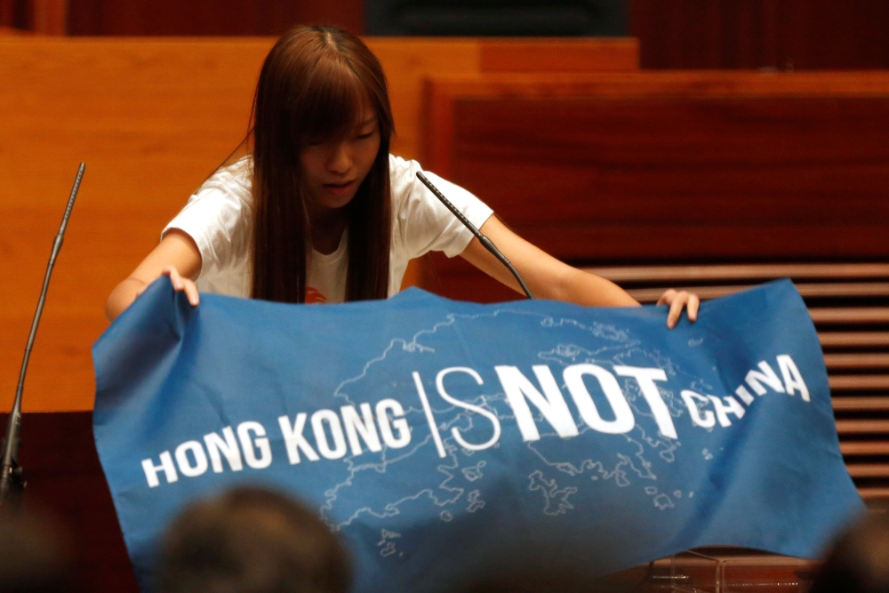 香港立法會新任議員12日宣誓就職，多位泛民主派（簡稱泛民派）議員在宣誓詞中「加料」表達理念。圖為青年新政新任議員游蕙禎在宣誓過程中拿出「香港不是中國」（Hong Kong is not China）的旗幟。（湯森路透）