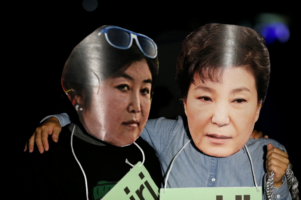 南韓總統朴槿惠的親信崔順實涉嫌干政，民眾帶著兩人肖像製成的面具上街抗議。（湯森路透）