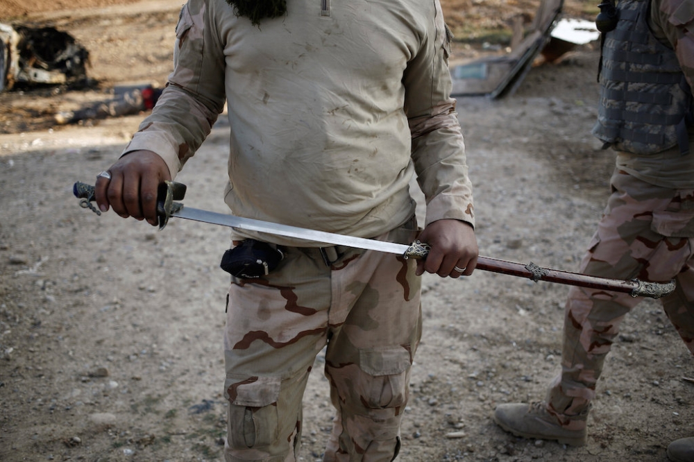 一名伊拉克士兵在摩蘇爾市內發現一把類似IS用來斬首的利劍。（湯森路透）