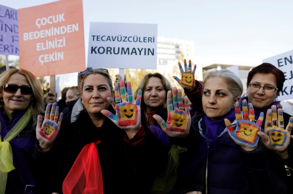 土耳其抗議民眾手持「不要對兒童出手」與「不要保護強暴犯」的字牌，抗議國會原將表決的童婚延刑草案。（湯森路透）