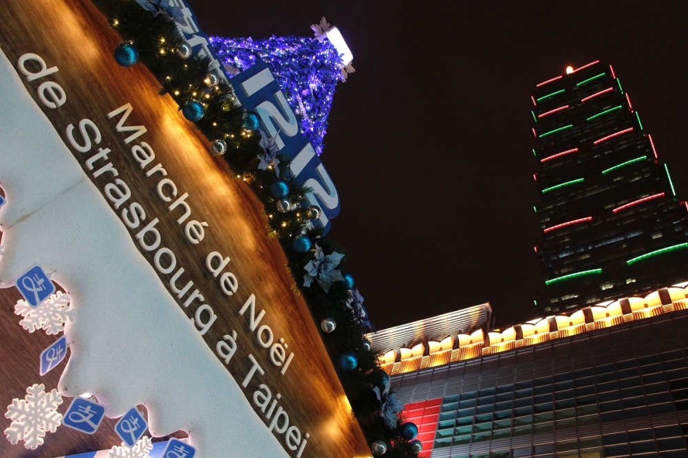 台北101水舞廣場的耶誕市集與打上紅綠相間燈光的101。（攝影：李隆揆）