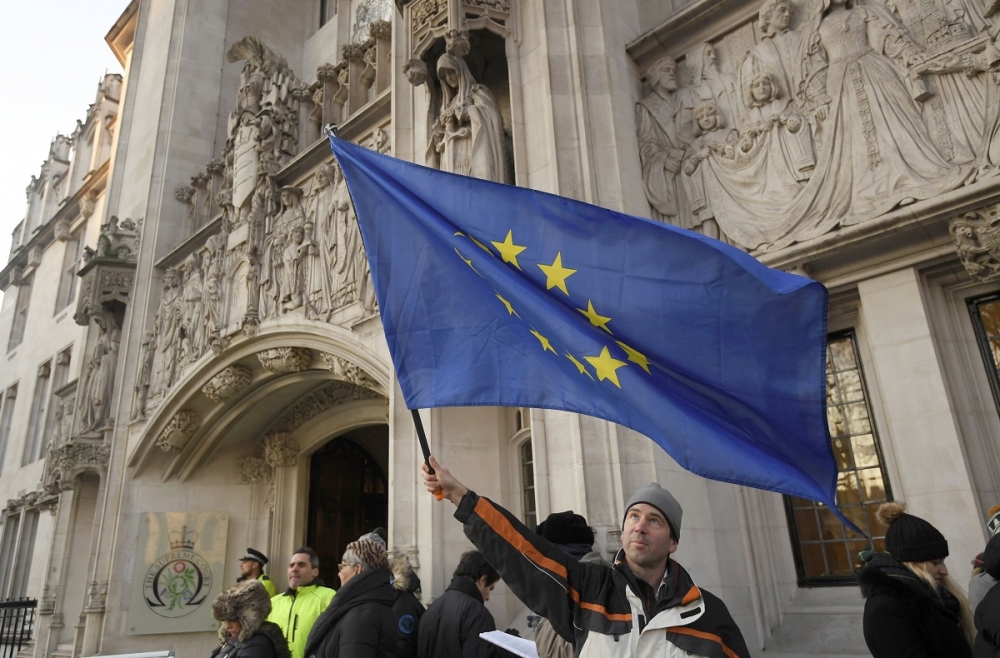 一名男子在倫敦中心的最高法院外揮舞歐盟旗幟。（湯森路透）