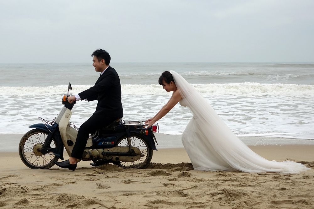 一名越南新娘和其夫婿在海邊拍攝婚紗照。（湯森路透）