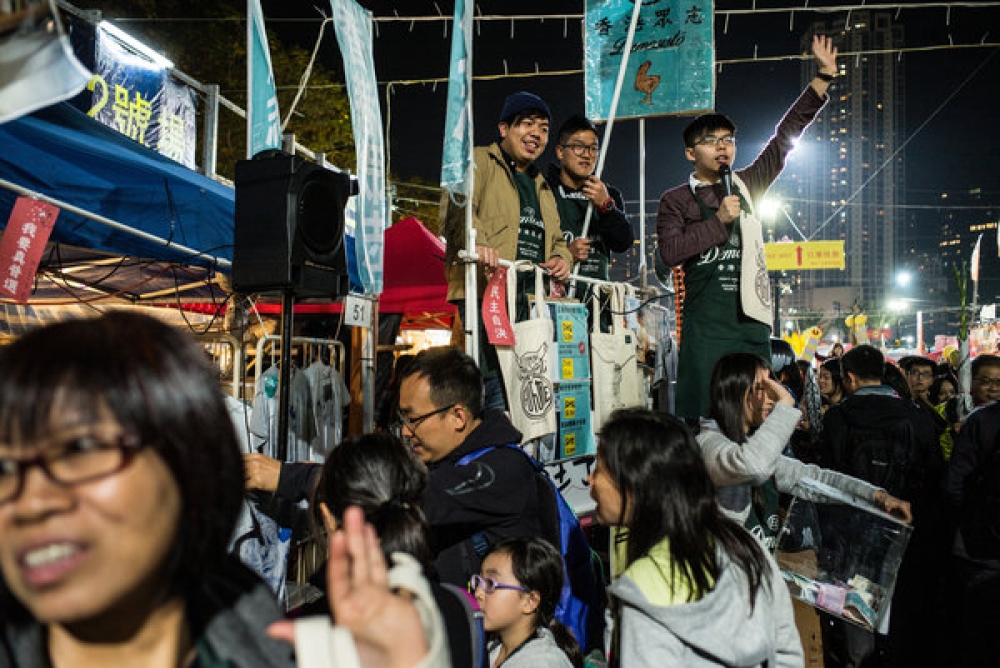 主張民主的「雨傘運動」領導者黃之鋒在維多利亞公園的年宵花市上發表講話。他參與創建的香港眾志黨在花市上有個攤位。  （紐約時報）