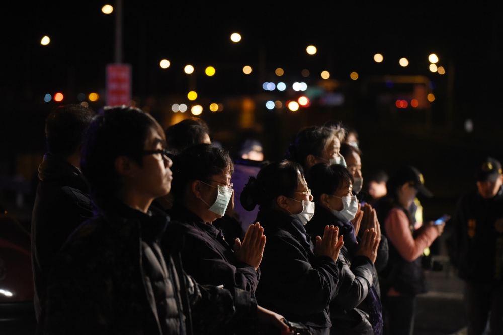 遊覽車嚴重翻覆意外釀32死，有人雙手合十祝念，場面哀戚。（攝影：葉信菉）