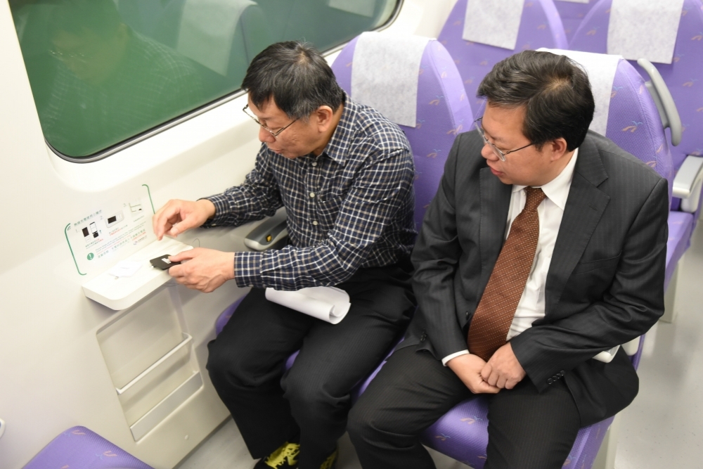 台北市長柯文哲15日體驗機捷乘車服務，他好奇的把玩著無線充電，似乎對無線充電很感興趣。（攝影：葉信菉）