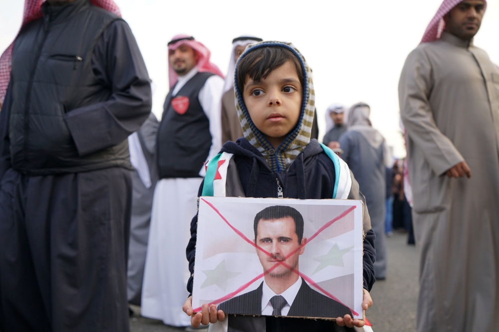 一名敘利亞孩童拿著反對敘利亞總統阿塞德的文宣。（湯森路透）