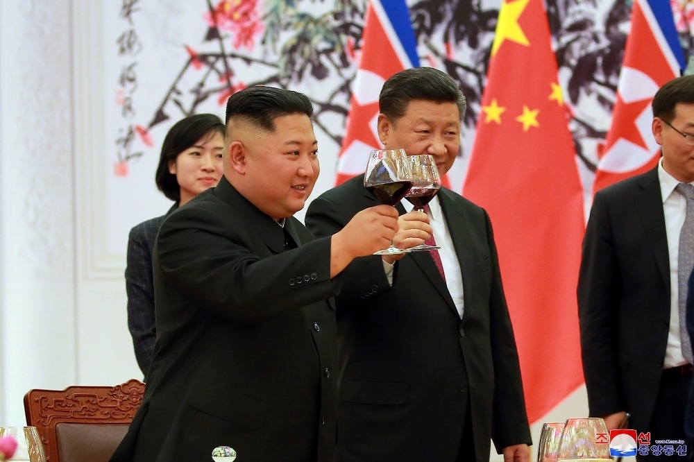 北韓領導人金正恩（左）19日與中國國家主席習近平（右）見面，報告川金會成果。（湯森路透）