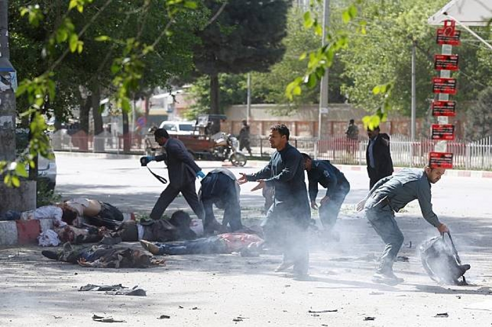 阿富汗警方協助第二場爆炸的受害記者。（湯森路透）