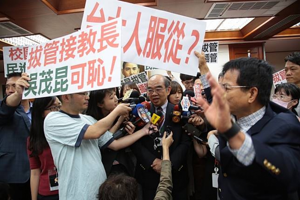 藍委在教育部長吳茂昆旁高舉標語抗議。（攝影：葉信菉）