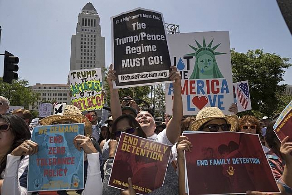 洛杉磯的民眾高舉標語，抗議川普政府拆散非法移民家庭。（美聯社）