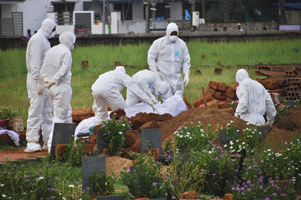 印度醫務工作人員將最新的病毒受害者埋在科澤科德鎮（Kozhikode），將屍體用塑料包裹埋入紅土中。（美聯社）