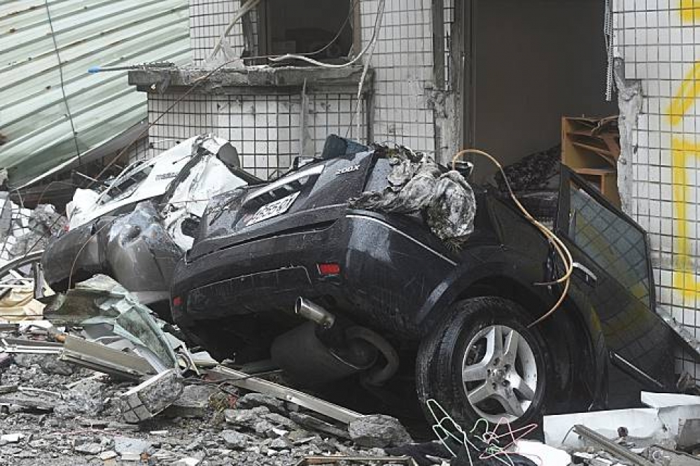 位於花蓮國盛六街的白金雙星大樓一樓，有許多車子被壓垮。（攝影：葉信菉）