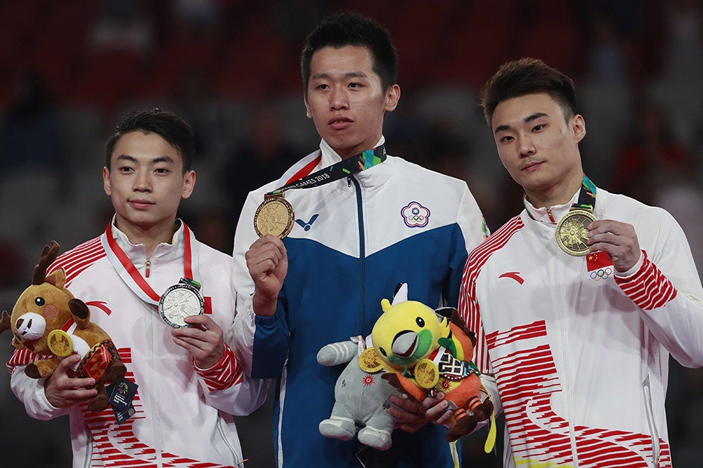 台灣在亞運獲取多個佳績，圖為李智凱（中）壓過中國選手，在亞運體操單項男子鞍馬項目摘下金牌。（美聯社）