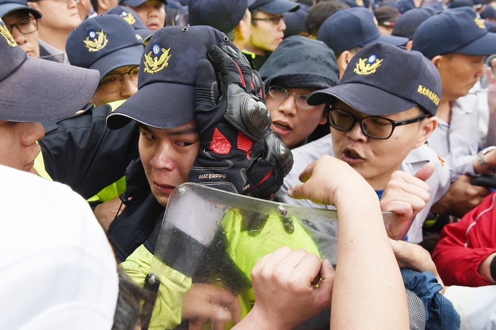 反年改抗爭中一名警察在激烈衝突中落下男兒淚，旁邊同袍用手撫慰他的臉頰，表達安慰。（攝影：葉信菉）
