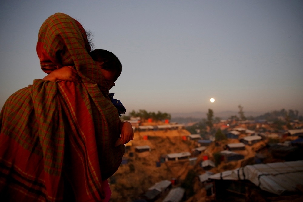 難民營內一名母親抱著她的孩子遙望滿月。（湯森路透）