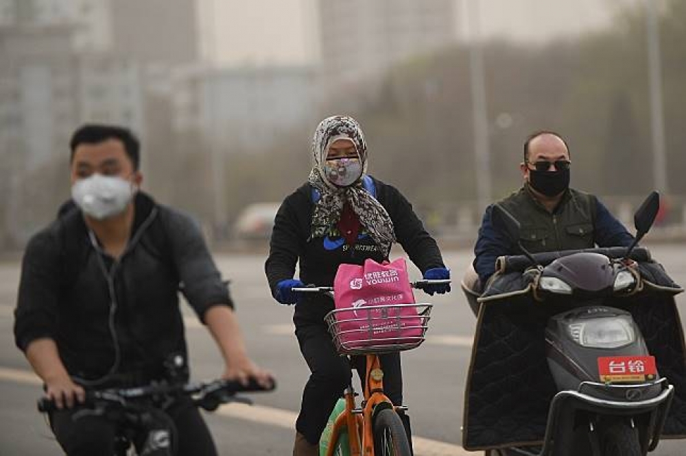 北京民眾外出戴口罩熬過沙塵暴天氣。（中新社）