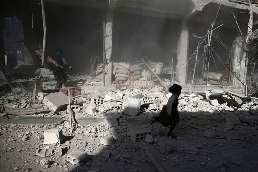一名敘利亞女童從炸毀的房屋前跑過。（湯森路透）
