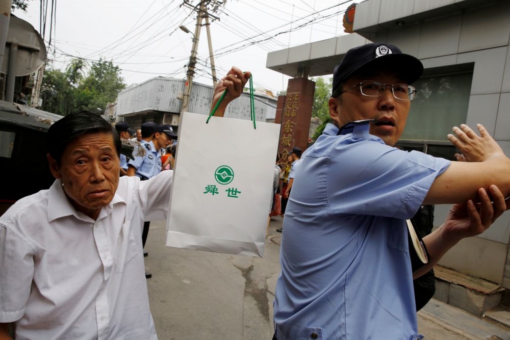 8月27日，1名中國P2P受害者（左）前往北京東城區公安部門前抗議。（湯森路透）