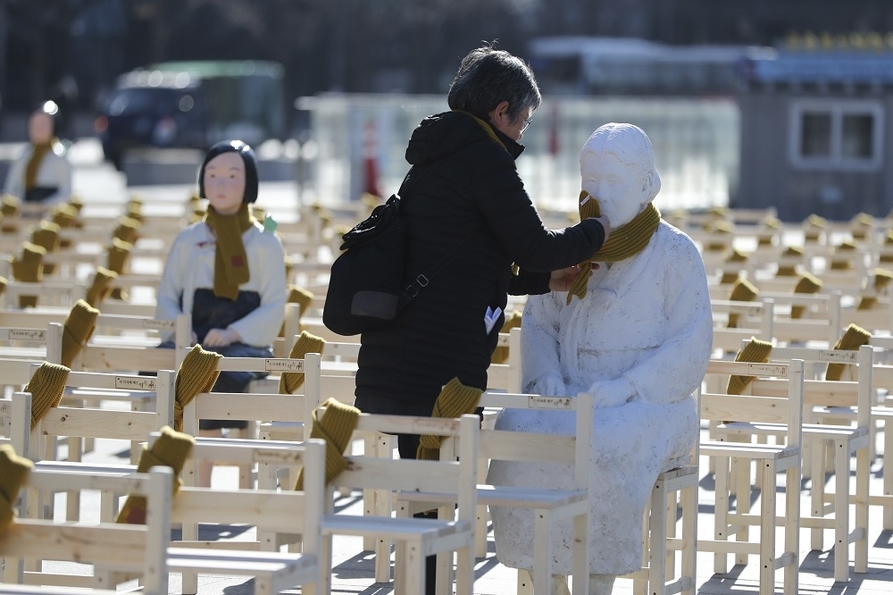 一名婦女為首爾的慰安婦雕像圍上圍巾。（美聯社）