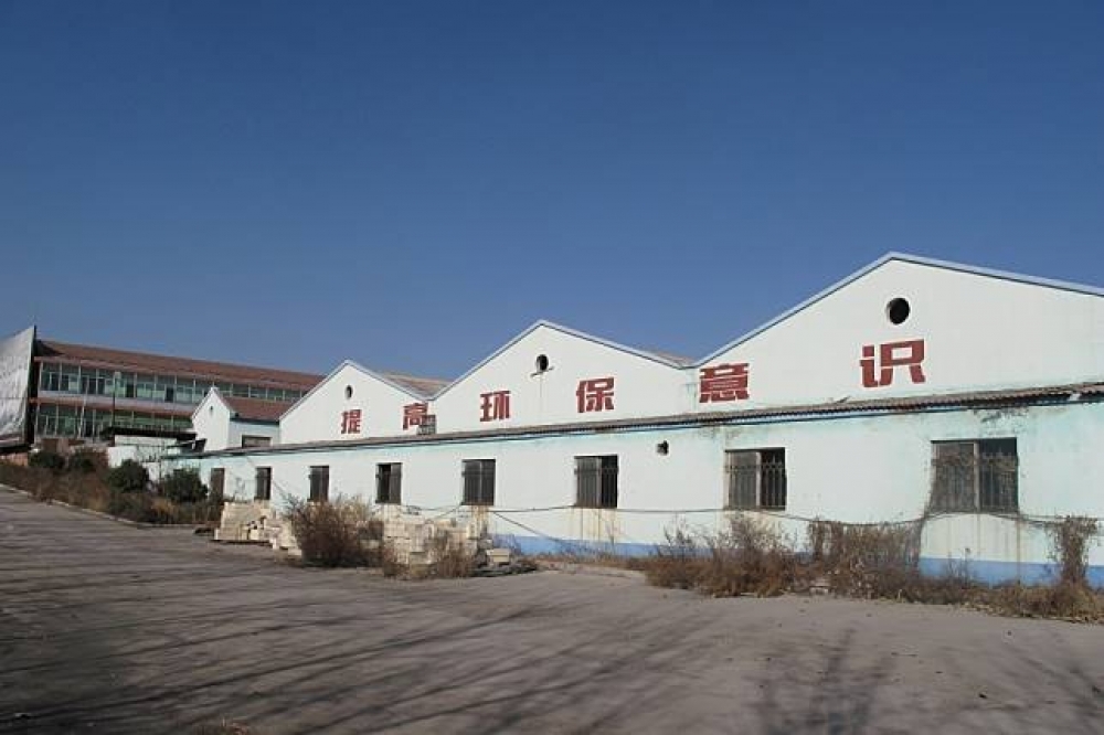中國山東的一間廢棄倉庫上印有「提升環保意識」的標語。（湯森路透）