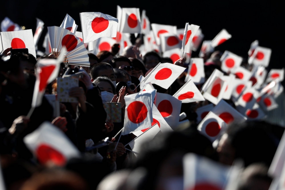 為慶賀明仁天皇誕辰，日本民眾揮舞國旗。（湯森路透）