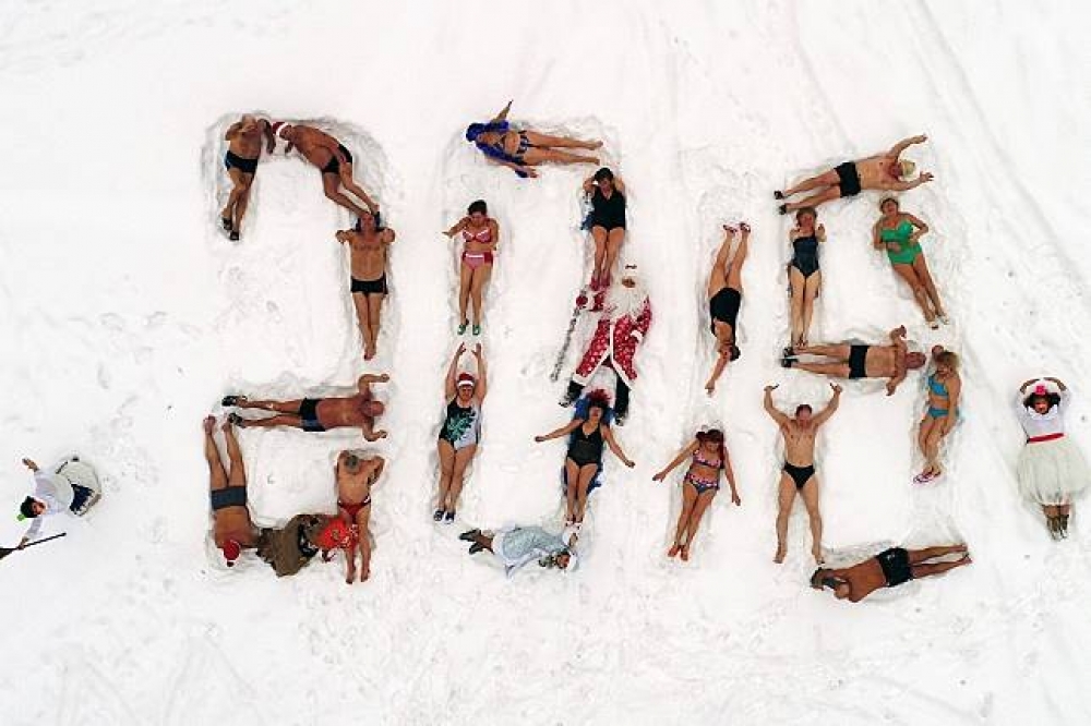 俄國克拉斯諾亞爾斯克一個冬泳俱樂部成員打扮成俄國版耶誕老人及雪姑娘，在雪地排出2018字樣。（湯森路透）