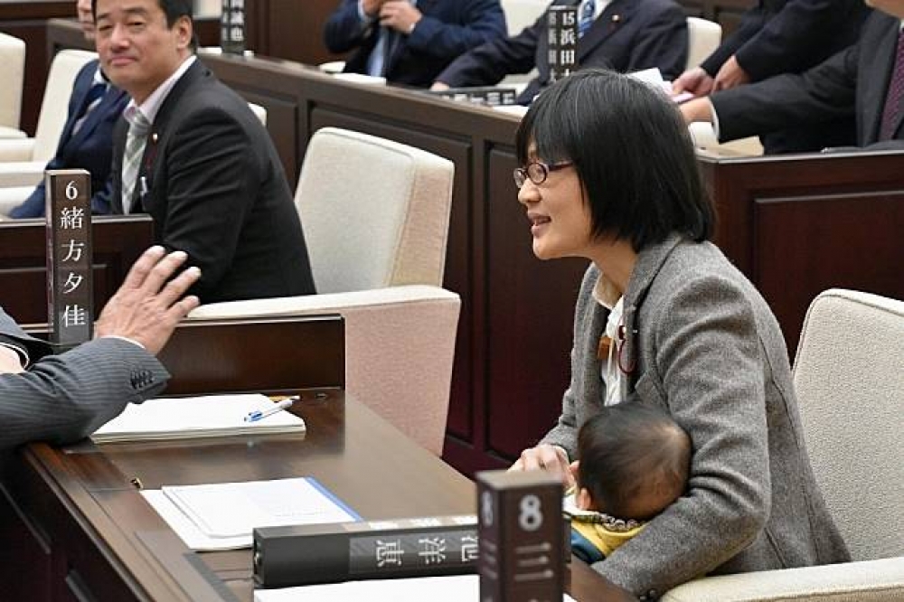 日本熊本市女議員緒方夕佳22日帶著兒子進入議事廳。（湯森路透）