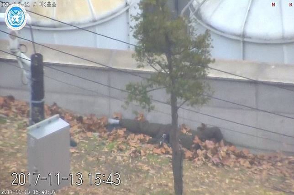 投誠士兵吳青成在被北韓士兵射傷後靠牆躺在落葉堆裡。（湯森路透）
