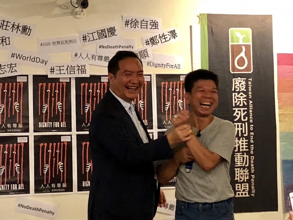 台灣廢除死刑推動聯盟邀請台灣的死刑平反者到場，政務委員羅秉成（左）拿著戒指對鄭性澤說：「希望廢死精神無所不在，這枚戒指陪伴你，也許讓你得到一些慰藉。」（攝影：王怡蓁）
