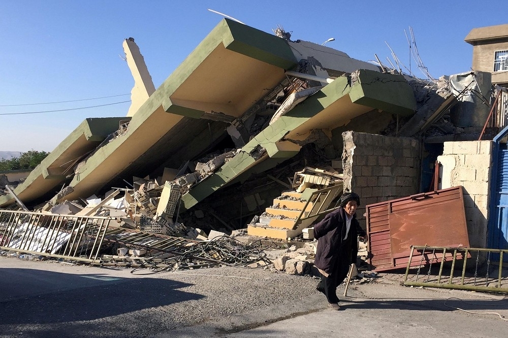一名男子行經因地震全數倒塌的建築。（湯森路透）