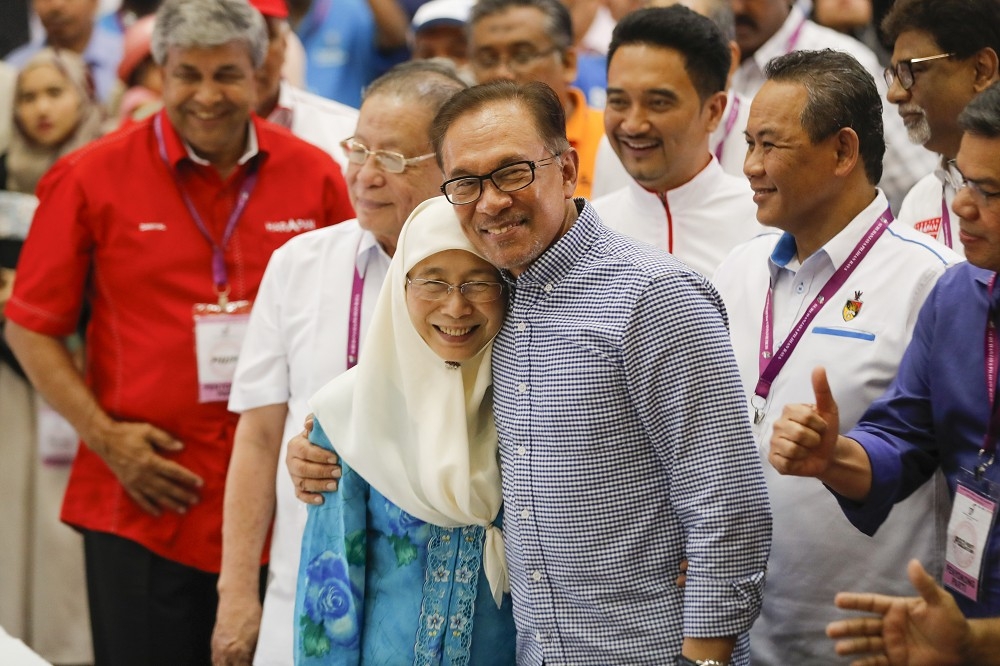 馬來西亞前副首相安華摟著妻子，接受當選國會議員的外界祝賀。（美聯社）