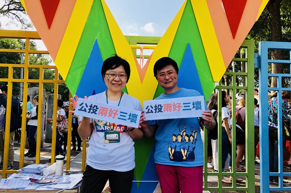 台灣伴侶權益推動聯盟製作三米高「超級彩虹V」，27日放置在228紀念公園前，代表同志平權將於年底選舉贏得勝利；左為伴侶盟秘書長簡至潔，右為律師許秀雯。（伴侶盟提供）