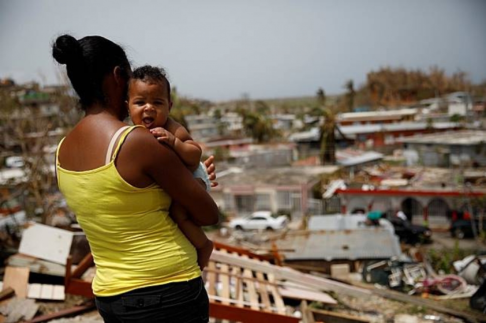 1名卡諾瓦諾斯（Canovanas）居民抱著她的孩子看著被摧毀的家園。（湯森路透）