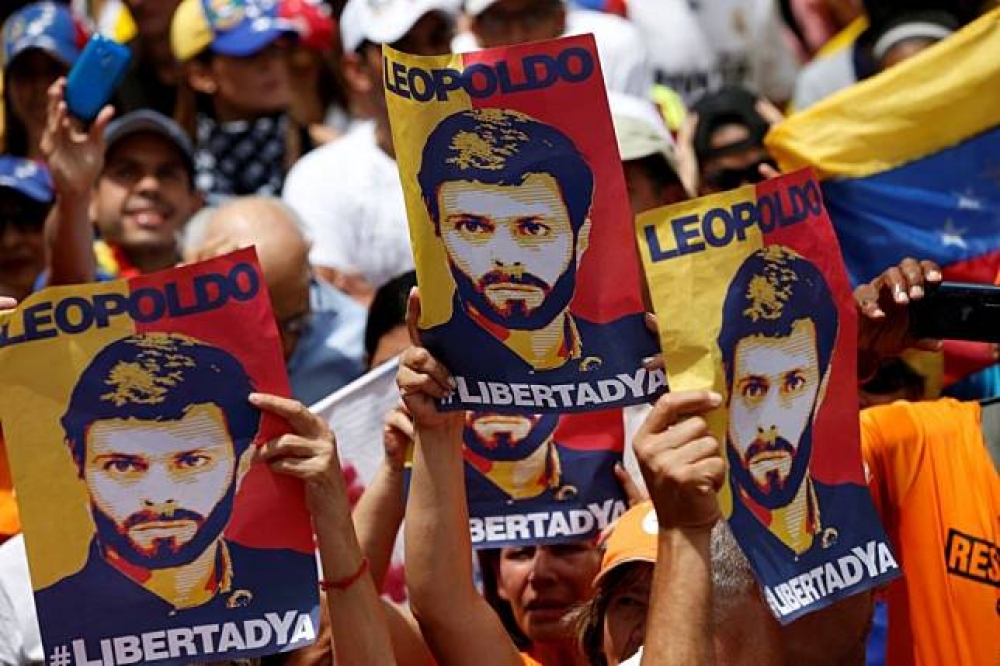 委內瑞拉民眾高舉反對黨領袖人像，反對總統馬杜洛。（湯森路透）