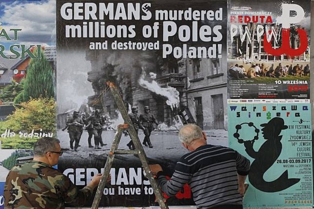華沙民眾在街道上貼海報，要求德國賠償波蘭二戰損失。（美聯社）