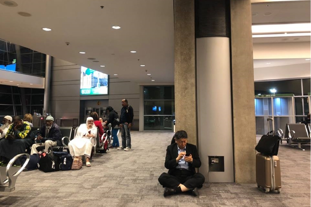 柯文哲於機場候機時，為了將手機充電而席地而坐，引發熱議。（圖片取自柯文哲臉書）
