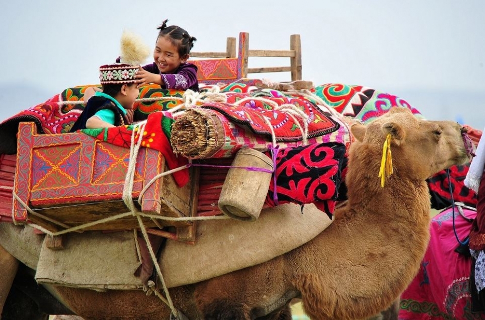 新疆維吾爾自治區內，2名兒童在駱駝上嬉戲。（湯森路透）