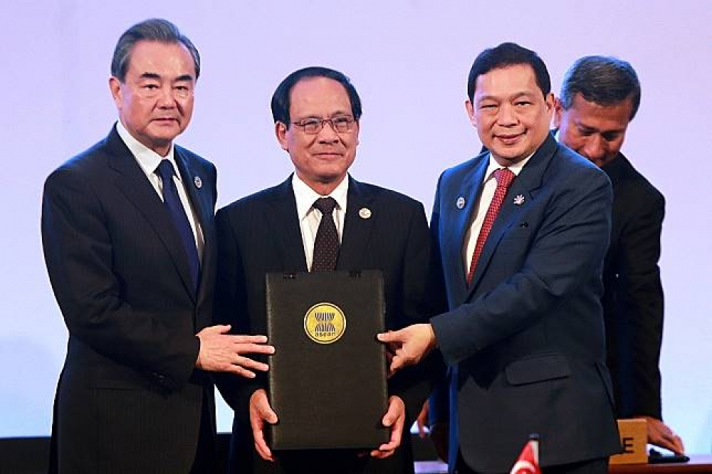 中國外交部長王毅（左起）、菲律賓外交部副部長特安凱（Manuel Teehankee）與東協秘書長黎良明手持備忘錄。（湯森路透）