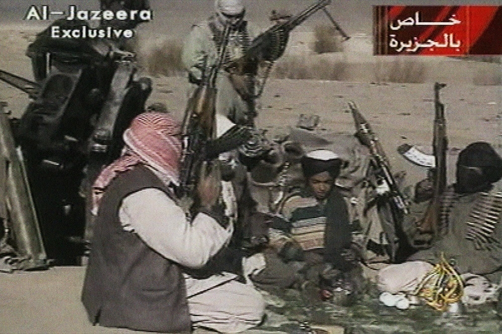 2001年11月5日，時年12歲的賓拉登之子哈姆札（Hamza bin Laden）身旁圍坐基地組織武裝份子。（美聯社）