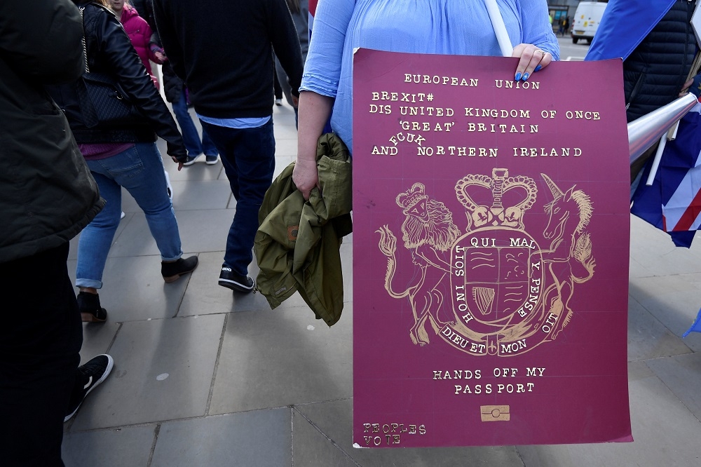 一名反脫歐的英國民眾，手持印用歐盟字樣的放大版封皮。（湯森路透）
