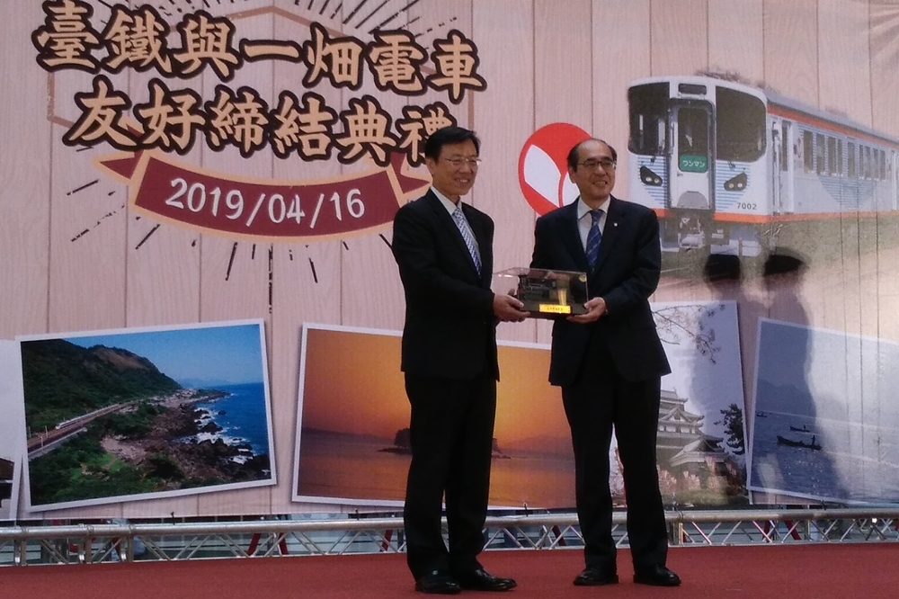 在友好條約簽署典禮上，台鐵局局長張正源（左）送給日本一畑電車代表取締役社長吉田伸司以台灣第一個蒸汽火車頭「騰雲號」為造型的130周年紀念酒（攝影：黃衍方）