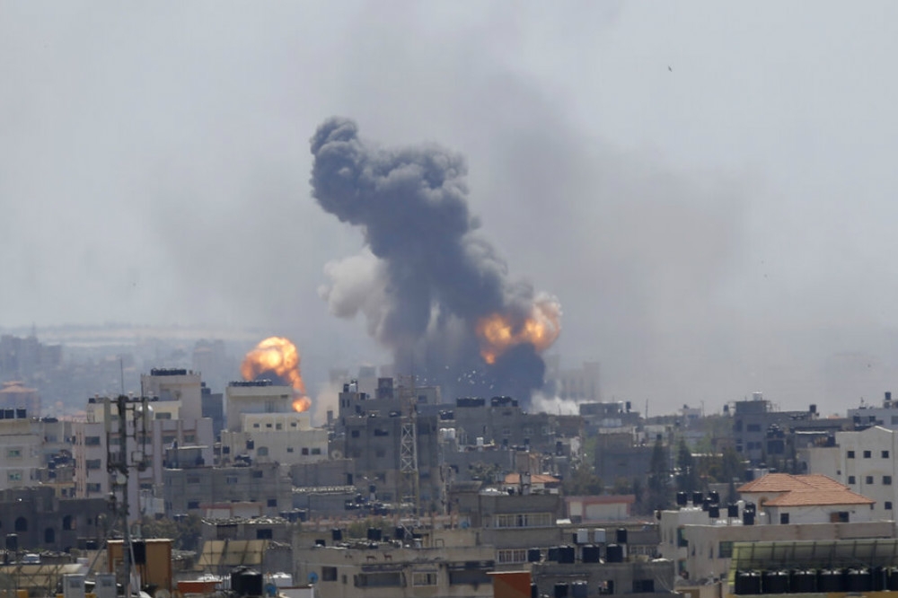 加薩市區遭以色列戰機空襲揚起的煙塵與火光。（美聯社）
