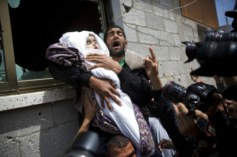 一家巴勒斯坦男子抱著遭空襲炸死、仍在襁褓中的孩子遺體痛哭。（美聯社）
