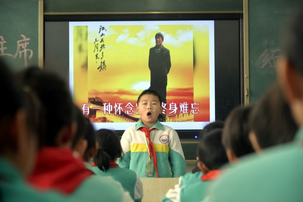 中國1名小學生站在毛澤東畫像前。（湯森路透）